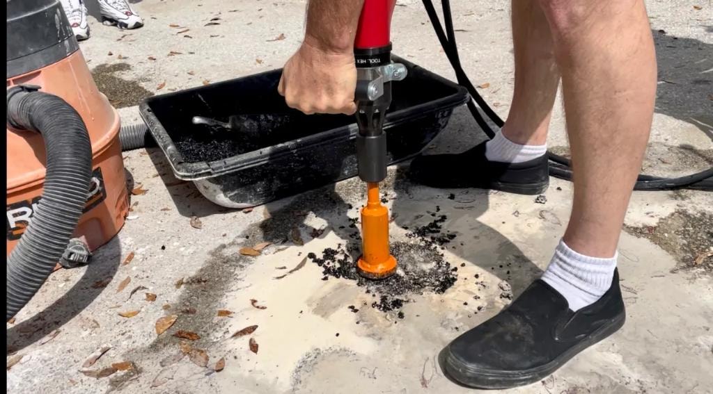 Operator core drilling into concrete pavement outdoors