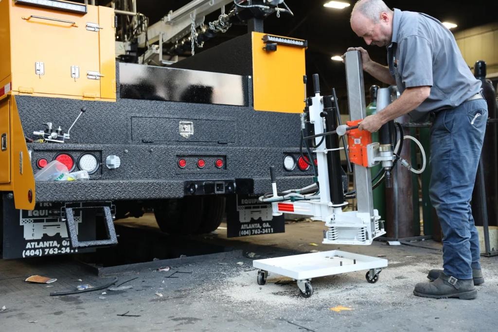 Technician adjusting core drill arm on service truck