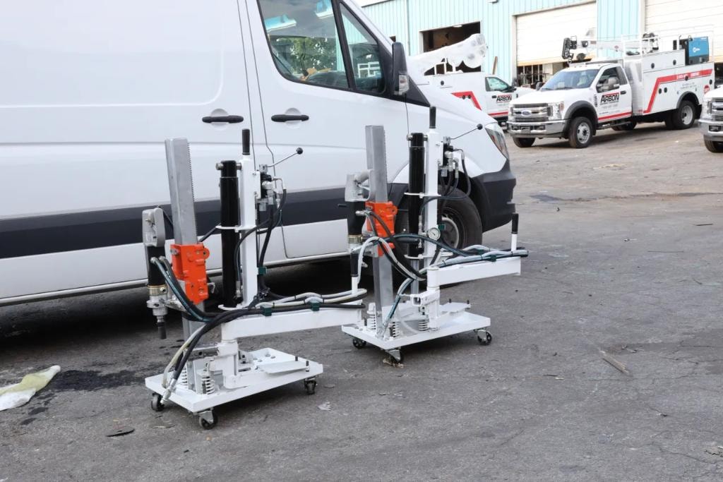 Two hydraulic core drill rigs on casters in front of white van