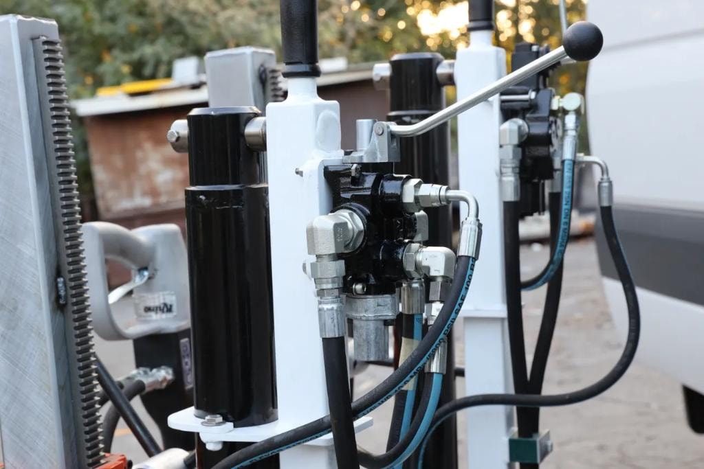 Close-up of hydraulic valve block and hose fittings on drill rig