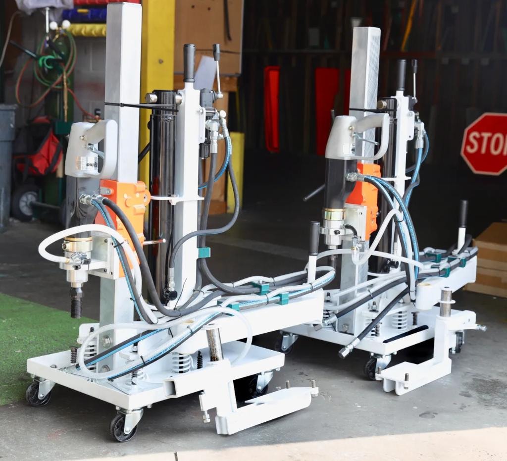 Two core drill rigs with orange motors inside workshop garage
